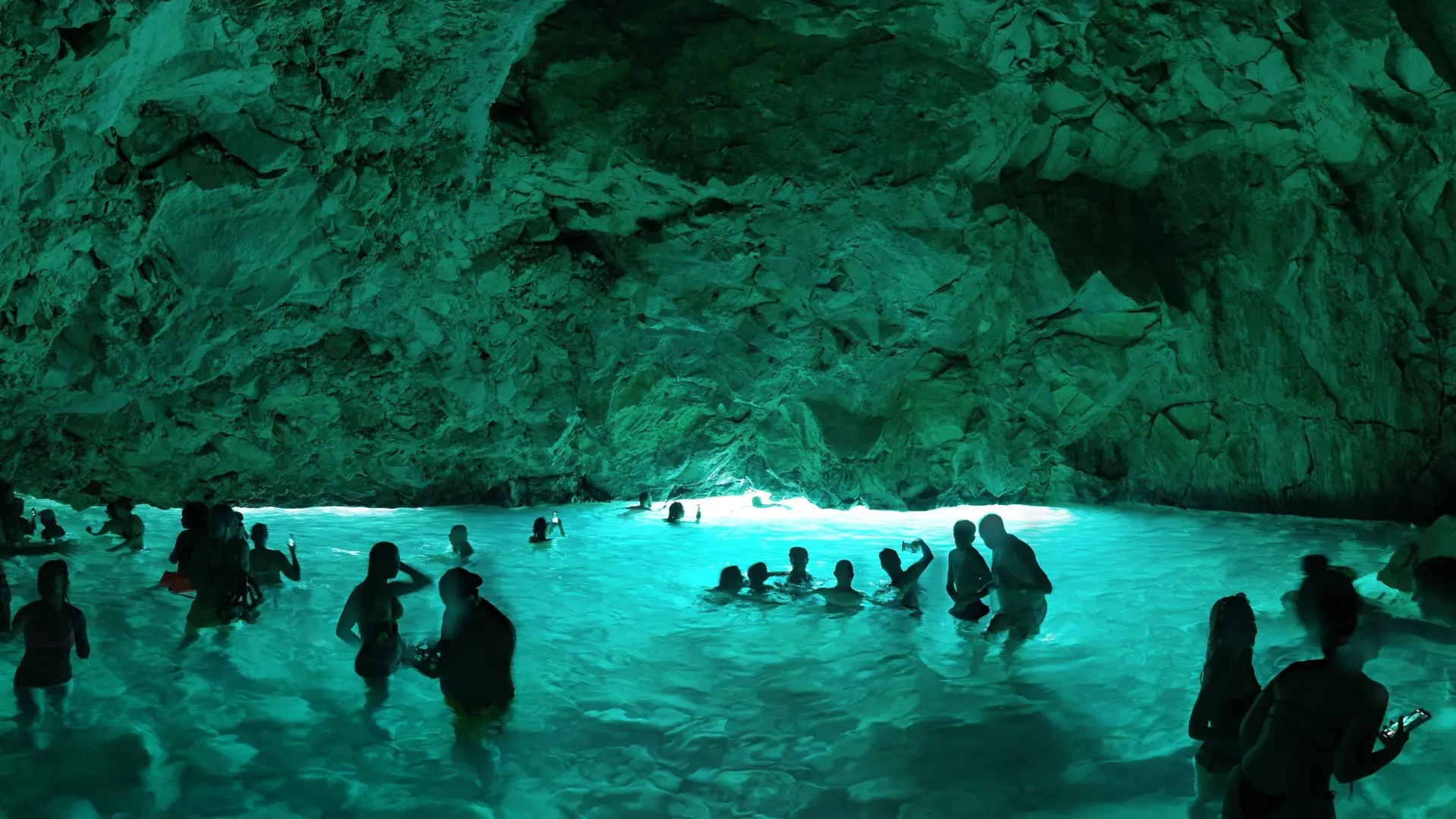 Besucher schwimmen im leuchtenden Wasser der Blauen Höhle